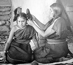 Fotografía histórica de una mujer hopi arreglando el cabello de una joven.