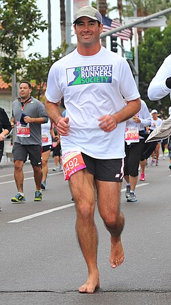Hombre corriendo descalzo durante una media maratón demostrando la técnica de apoyo