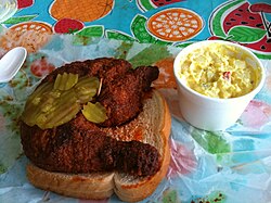 Hot chicken al estilo de Nashville con guarnición tradicional.