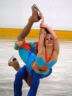 Elevación con el patinador agachado y su pareja en posición biellmann.