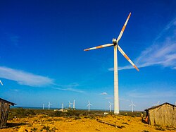Aerogenerador junto a viviendas tradicionales en una zona desértica.
