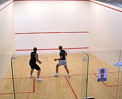 Dos personas jugando a squash en una pista interior
