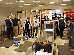 Escáner de equipaje y arcos detectores de metales en controles aeroportuarios.