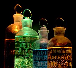 Soluciones y sustancias en botellas de reactivos iluminadas de diferentes colores.