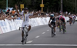 Ciclista cruzando la línea de meta celebrando la victoria