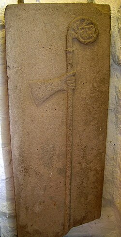 Brazo y báculo típico cisterciense en lápida funeraria de abad.