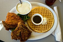 Plato de pollo frito con gofres, conocido como chicken and waffles, representativo de la gastronomía sureña.
