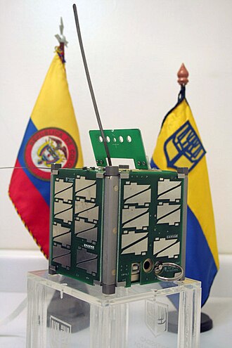 Satélite Libertad 1 en exhibición junto a banderas institucionales