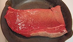 Filete de vaca sobre una sartén a punto de ser cocinado