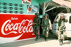 Soldados junto a un cartel publicitario de Coca-Cola