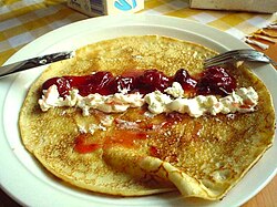 Crepe abierta con crema de leche y mermelada de fresa.
