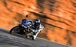 Motocicleta deportiva en desplazamiento sobre terreno inclinado.