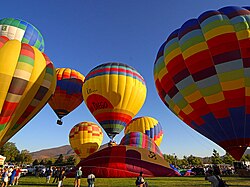Flota de globos de aire caliente sobrevolando un paisaje urbano.