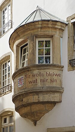 Inscripción de Mir wëlle bleiwe wat mir sinn en una fachada en Luxemburgo.