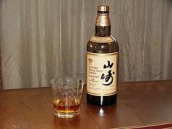 Un vaso y una botella de whisky de malta Suntory de 12 años Yamazaki.