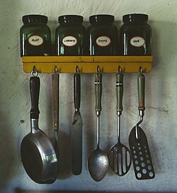 Botes de especias y utensilios de cocina colgados en un estante