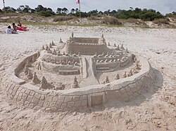 Estructura temporal esculpida con arena en una playa.