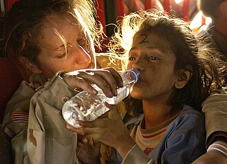 Sargento del ejército estadounidense dando agua a una joven paquistaní en un helicóptero en 2005.