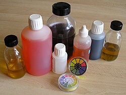 Varios indicadores de pH en recipientes con muestras líquidas.