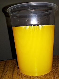 Vaso desechable con jugo de naranja industrializado