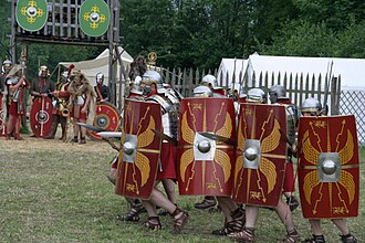 Representación de legionarios romanos avanzando en formación de ataque.