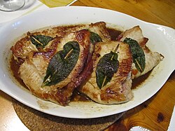 Plato de saltimbocca preparado con carne de pollo y guarnición.