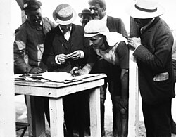 Fotografía histórica de Lucien Petit-Breton firmando documentos tras su victoria en el Tour de Francia de 1907