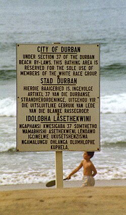 Advertencia trilingüe en una playa de Durban indicando uso reservado a blancos según la sección 37.