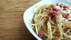 Plato de pasta carbonara con abundante pimienta negra espolvoreada por encima.