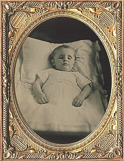 Fotografía de un niño muerto simulando estar dormido.