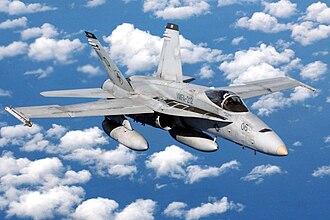 Un F/A-18 Hornet en vuelo con depósitos externos de combustible.