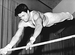 Competidor ejecutando una rutina en la barra alta durante una competición en 1967.