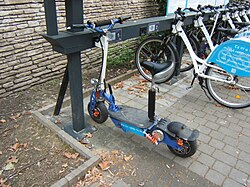 Una estación para aparcar bicicletas compartidas y un patinete eléctrico
