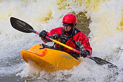Kayak navegando a través de rápidos en un río de aguas bravas.