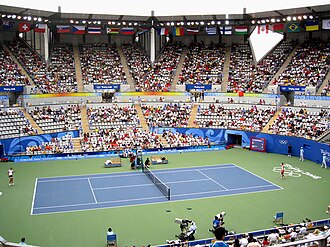 Interior del Centro de Tenis del Parque Olímpico de Pekín mostrando las gradas y las pistas