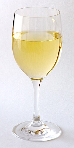 Una copa de vino blanco servida con reflejos claros.