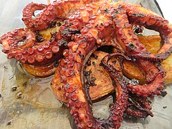 Plato de pulpo cocinado y servido en un puerto gastronómico.