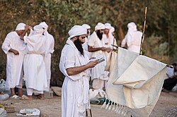 Miembros de la comunidad mandea congregados en oración junto a una fuente de agua.