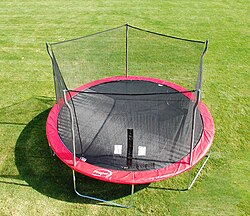 Cama elástica recreativa equipada con una malla de protección lateral.