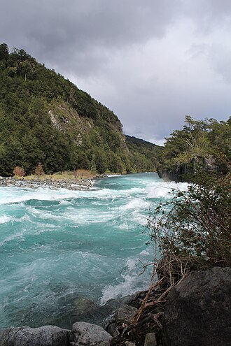 Caudalosas aguas blancas fluyendo entre rocas volcánicas oscuras