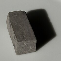 Bloque de metal de wolframio sólido sobre superficie neutral.