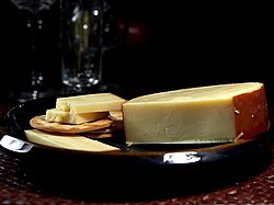 Queso gouda ahumado en rodajas mostrando su característica corteza oscura