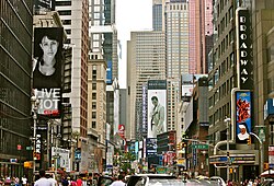 Escena diurna con tráfico y peatones en una sección transitada de Broadway.