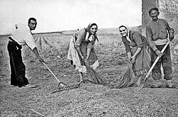Familia campesina preparando cereal para la trilla en un entorno rural tradicional.