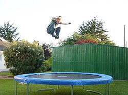 Un joven saltando en una cama elástica al aire libre.
