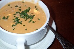 Una taza de bisque de langosta decorada con trozos del marisco.