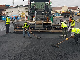 Trabajadores esparciendo mezcla asfáltica en una obra de pavimentación.