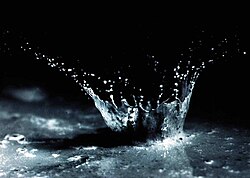 Suelo y agua salpicados por el impacto de una gota de lluvia