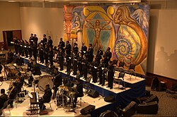 Integrantes de una agrupación coral cantando en un recinto académico.