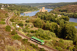 Composición ferroviaria circulando junto al castillo medieval de Almourol